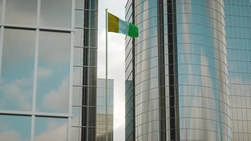 3D-Renderanimation der Flagge von Côte d'Ivoire auf einem Mast mit Stadtgebäuden