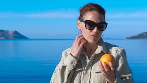 Woman with Orange Outside by the Ocean