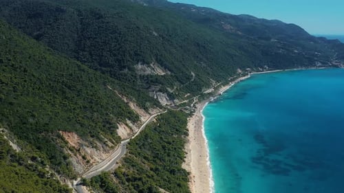 Aerial View of Coastal Road Alongside a Turqouise Beach