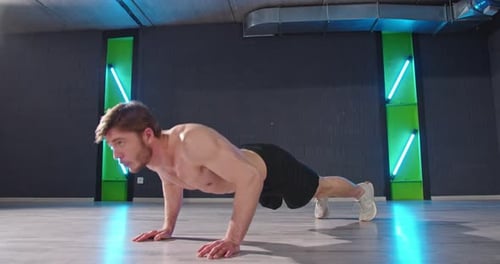 Full Length View of the Young Athletic Man Doing Pushups of the Floor While Training at the Dark Gym
