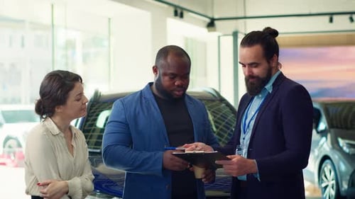 Un agent d'une salle d'exposition de voitures suggère aux clients des fonctionnalités supplémentaires à acheter et demande une signature