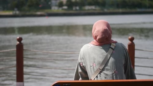 Woman Sitting on Bench by Water