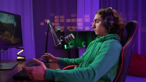 Junger erwachsener Mann verbringt Zeit zu Hause Mann Streamer Gamer sitzt am Schreibtisch mit Computer im Neonlicht