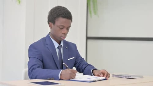 African Businessman Doing Paperwork in Office