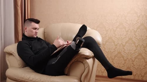 Young Man Relaxing and Reading a Book Indoors