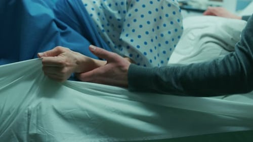 En el hospital, una mujer en trabajo de parto empuja para dar a luz, momento tenso en el que agarra sábanas con dolor. Cara Cl