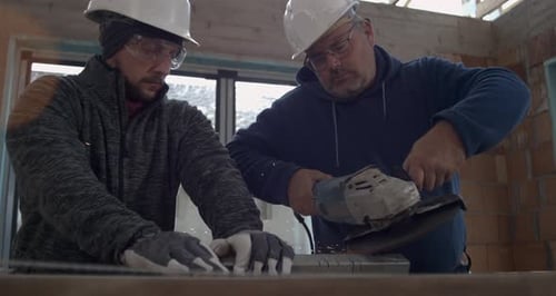 Construction Workers Cutting Metal With Grinder Indoors