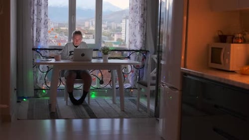 Woman works at home sitting in computer, looking at monitor screen on living room and kitchen