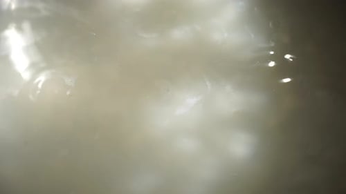 Nahaufnahme weiße Suppe kochend, Spiegelungen im kochenden Wasser
