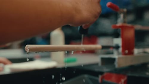 Water droplets dripping down golf club shaft as male builder's hands squeeze water onto grip to prep