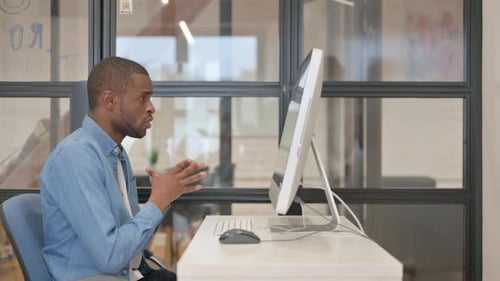 African Businessman Doing Online Video Chat on Desktop in Office