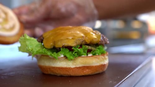 Putting a bun on a cheeseburger- close up