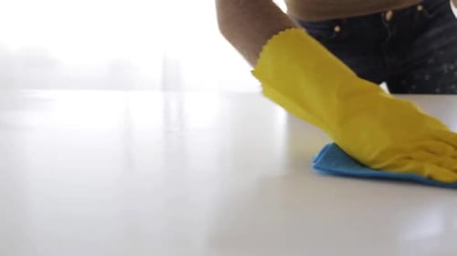 Person Cleaning White Surface with Spray and Cloth
