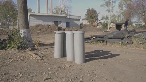 Concrete Tubes and Industrial Building on a Dirt Ground