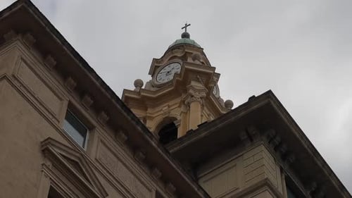 Schwenklammer mit Blick nach oben auf den Kuppelturm der Kirche mit verziertem Ziffernblatt und dekorativem Traufen von