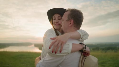 Tender Embrace of Smiling Lovers at Sunset in a Grassy Field