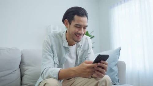 Man Relaxing on Couch Using his Cellphone