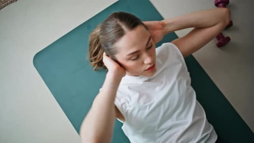 Frau spielt Situps Fitnessmatte drinnen, Nahaufnahme, Ansicht von oben, energetisches Mädchen