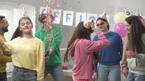 A Group of Colleagues in Festive Hats and Glasses are Dancing Having Fun Celebrating a Common