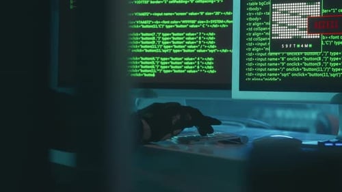 Gloved Hacker Typing on Computer in Dark Office