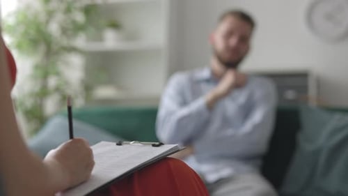Man Attends Therapy Session with Note Taking Therapist