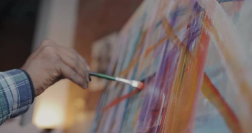Closeup of Hand Holding Paintbrush Creating Masterpiece Painting Colorful Picture on Canvas