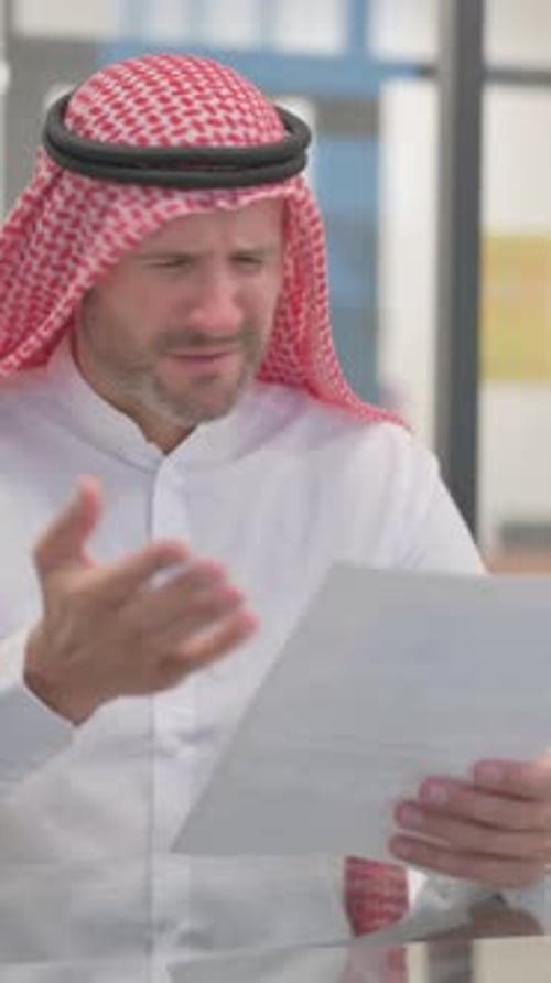 Worried Man in Keffiyeh Examining Documents at Desk