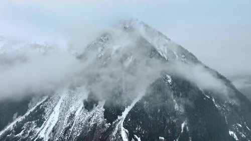 Vue spectaculaire sur l'immense mont recouvert de brouillard. Il y a de la neige sur la montagne