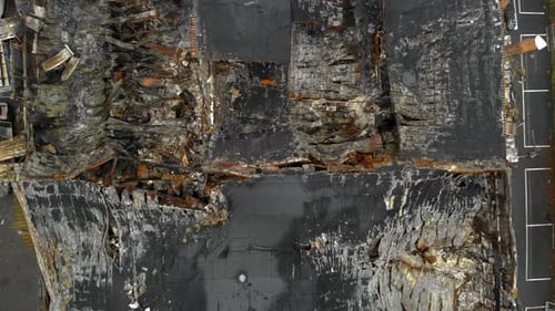 Aerial view of burned down building after devastating fire, zooming out shot