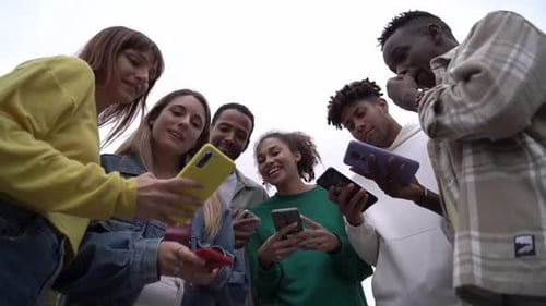 Diverse Group of Young Adults Sharing Smartphones