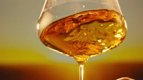 Orange or White Wine Bottle and Glass Against a Sunset in a Peaceful Vineyard Pouring of Ecological