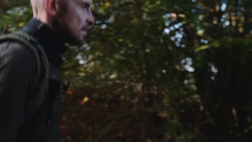 Side View of a Man Tourist with Backpack Hiking Along the Trail in the Forest