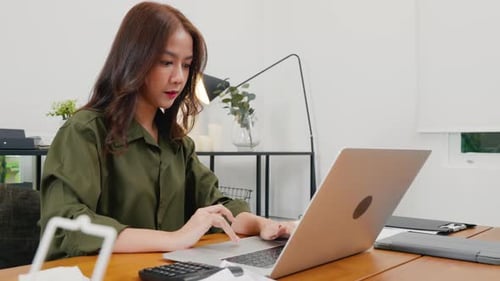 Asian Young Business Woman Freelancer Working with Laptop Computer and Calculator at Home Office