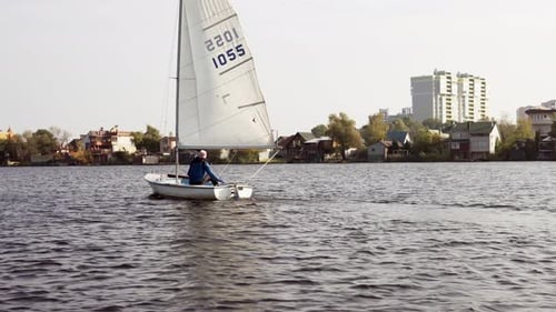 A yachtsman walks along the river on a sailboat in the cold season. Travel, tourism, recreation.