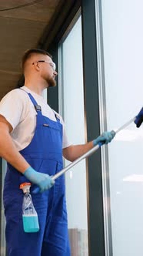 Concierge professionnel lavant les grandes fenêtres de bureau