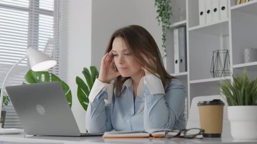 Woman with Headache Working at Laptop in Office