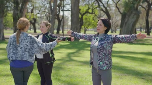 Yoga Instructor Helping Women during Practice in the Park