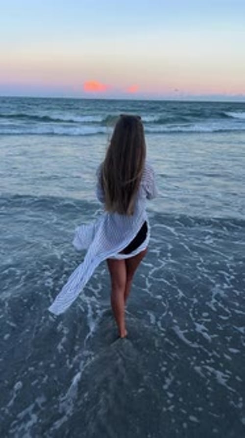 A Woman Enjoys Beach Tranquility at Sunset Reflecting and Peaceful