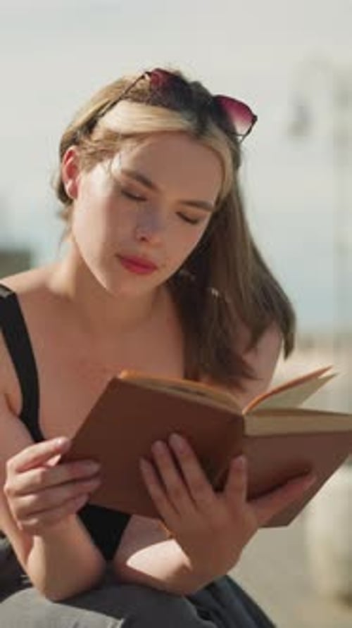 Woman Reading a Book Outdoors in City