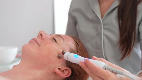Beautician Massaging Face of Woman with Special Tool in Beauty Spa