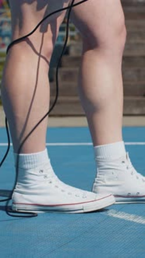 Closeup of Athletic Man Legs Skipping Rope Doing Jumping Exercises on Basketball Court Outdoors
