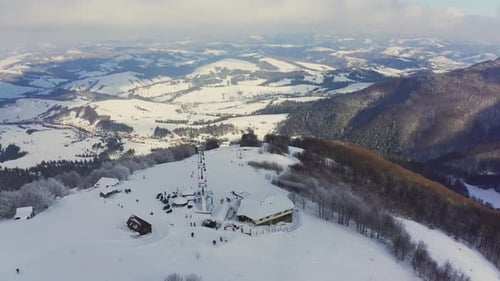 Alte Skistation an einem verschneiten Berghang mit vielen Menschen auf Skiern und Snowboards