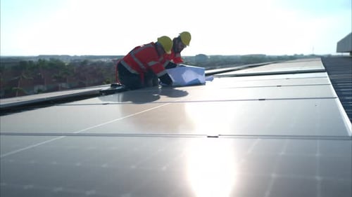 Engineer and technician working on the solar panel on the warehouse roof to inspect the solar panels