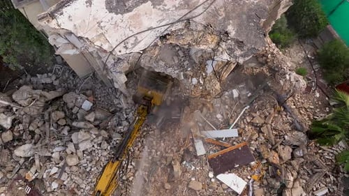 Building demolition excavator using Pulverizer Jaws to demolish a residential building