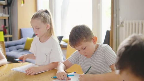 A Portrait of an Elementary School Boy and Girl Deeply Focused on Their Drawings During an Art