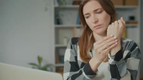 Woman Massaging Sore Wrist at Desk
