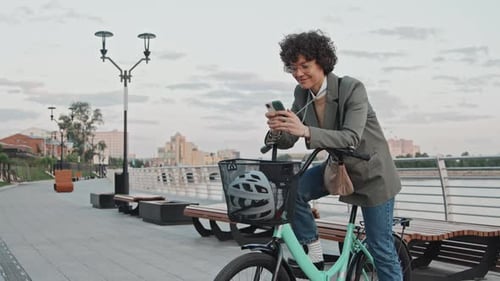 Woman With Bike Using Mobile Phone in City