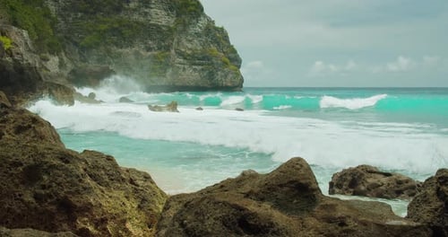 Ocean waves crash on rocky tropical beach