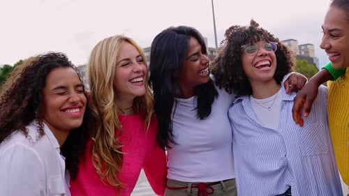 Grupo de mulheres multiétnicas se abraçando enquanto riem na rua da cidade