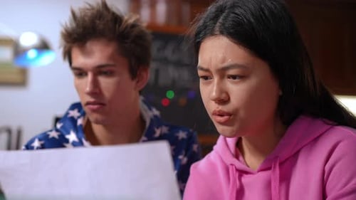 Fille concentrée qui parle, analyse de la paperasse avec un garçon, pense